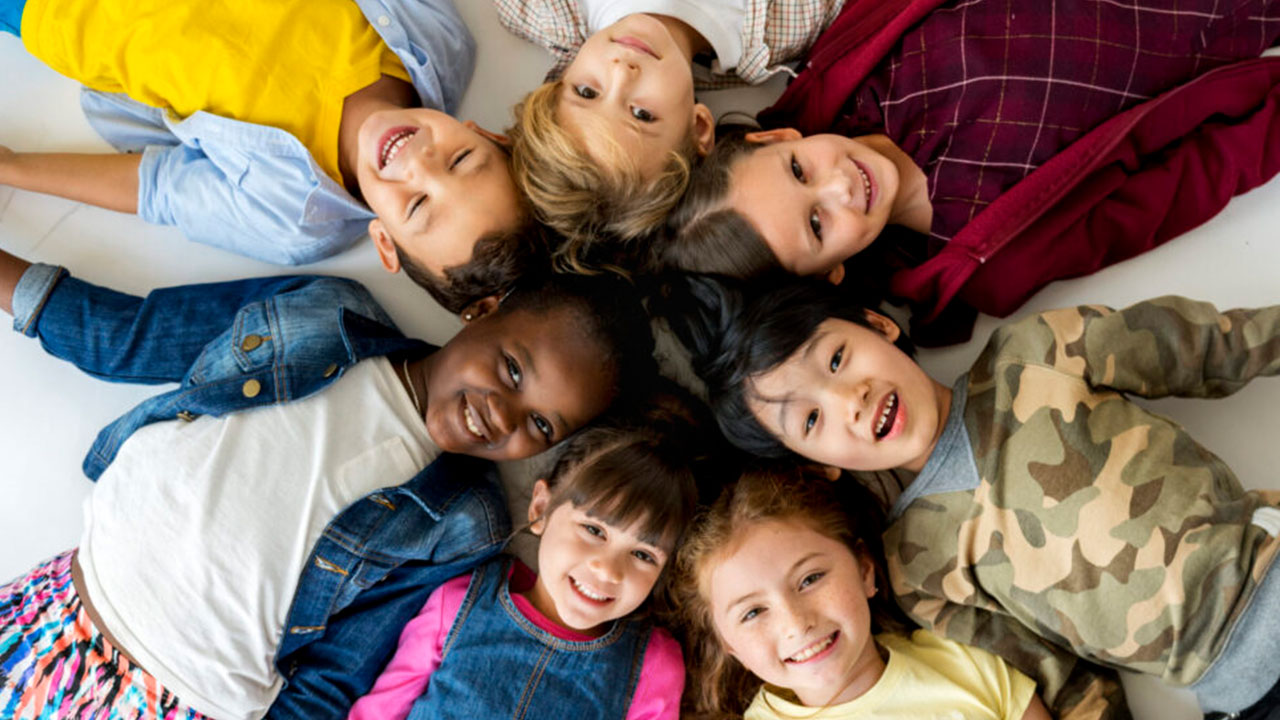 A group of primary schoolers lying on the ground and smiling